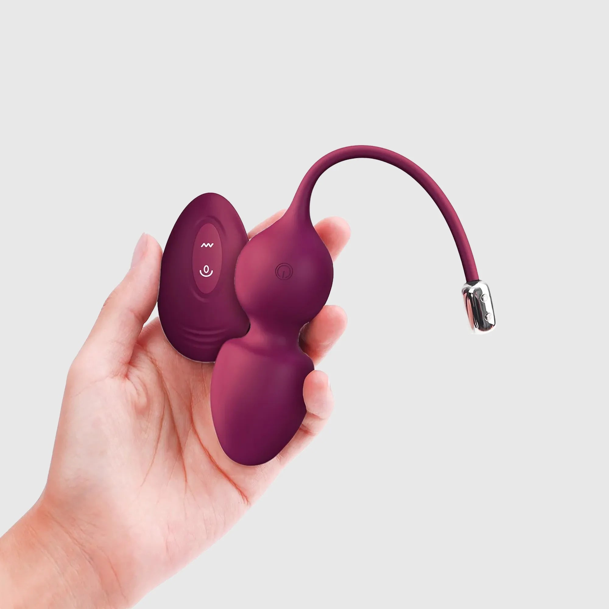 Boules de geisha télécommandées Love Balls Plum, montrées dans une main pour illustrer leur taille