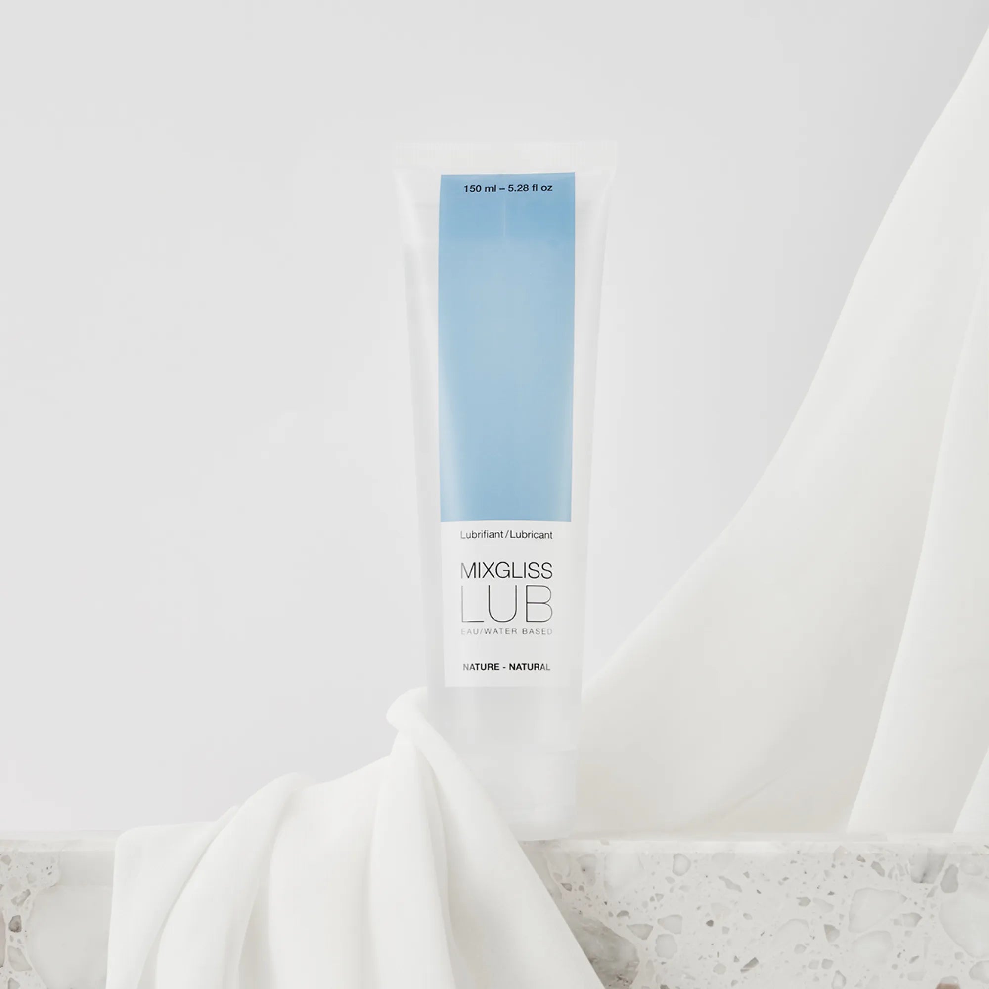 Tube de lubrifiant Mixgliss Eau Nature posé sur un tissu blanc, ambiance élégante et épurée.