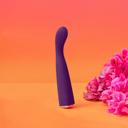 Vibromasseur Feel Me violet mis en scène avec un fond coloré et des fleurs