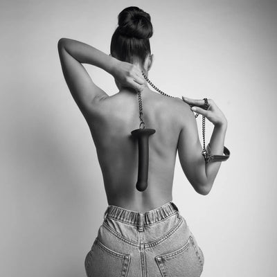 Femme de dos tenant un gode avec anneau et chaîne – illustration de jeu BDSM intime