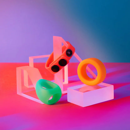 Mise en scène des trois cockrings en silicone du Kit Neon Ring, posés sur des cubes colorés pour illustrer leur style ludique