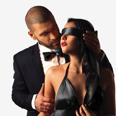 Couple élégant avec bandeau satin noir sur les yeux, ajoutant une touche sensuelle aux jeux BDSM.